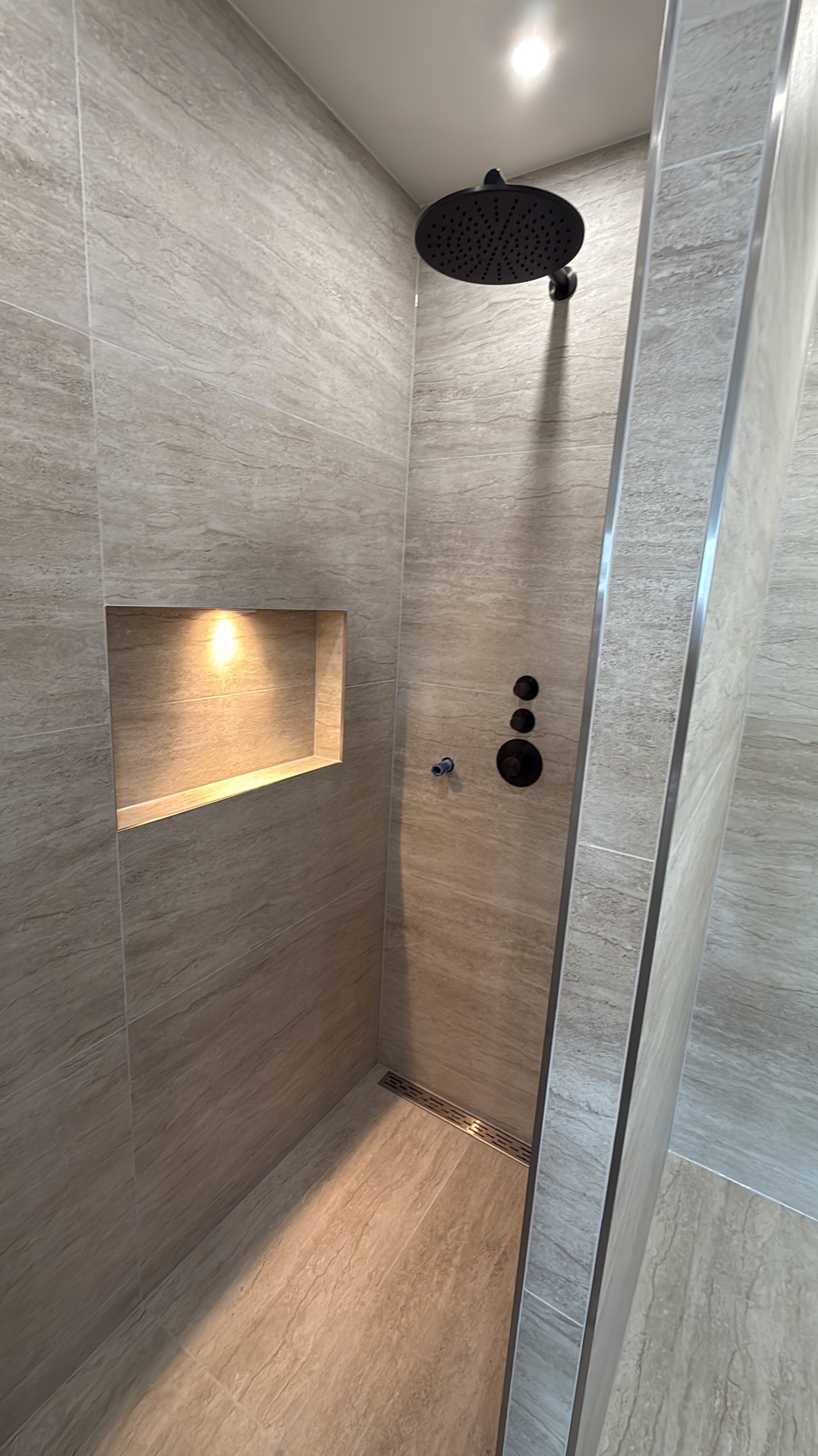 Detail inloopdouche met zwarte douchebediening en lineaire afvoer — project Amsterdam